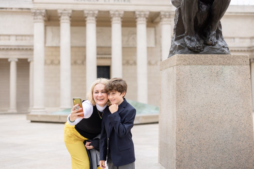 a mom and son take a selfie in front of a statue