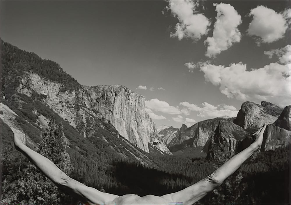 Black and white photograph of Yosemite with Minkkinen’s outstretched arms mirroring the curve of the valley