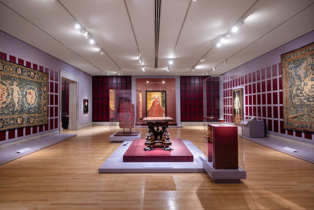 Tapestries, paintings, and luxury goods on display in an exhibition gallery.