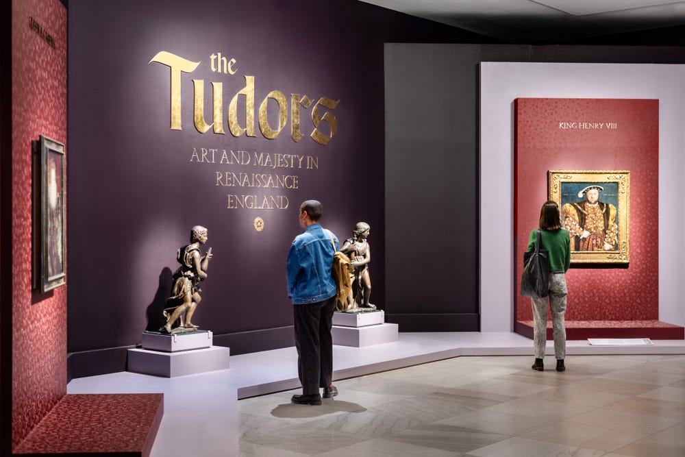 Two people looking at artwork in the entrance room of the Tudors exhibition.