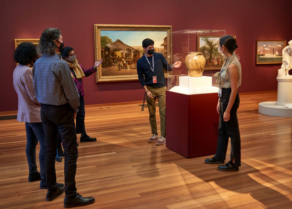 people in a de Young gallery looking at an object