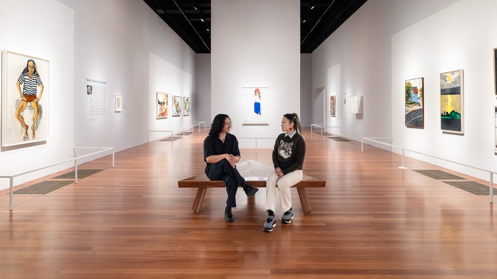 two people sitting next to each other in a gallery