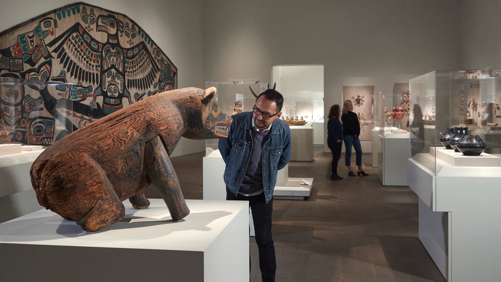 man looking at bear sculpture in gallery