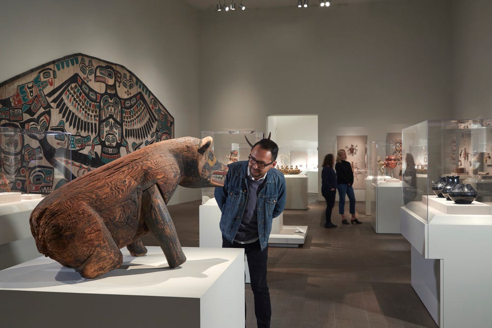 man looking at bear sculpture in gallery