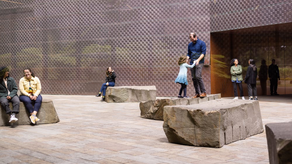 people sitting and standing on rock sculptures in a courtyard
