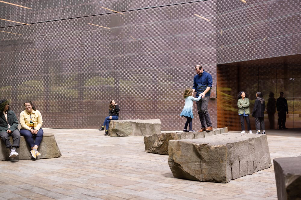 people sitting and standing on rock sculptures in a courtyard