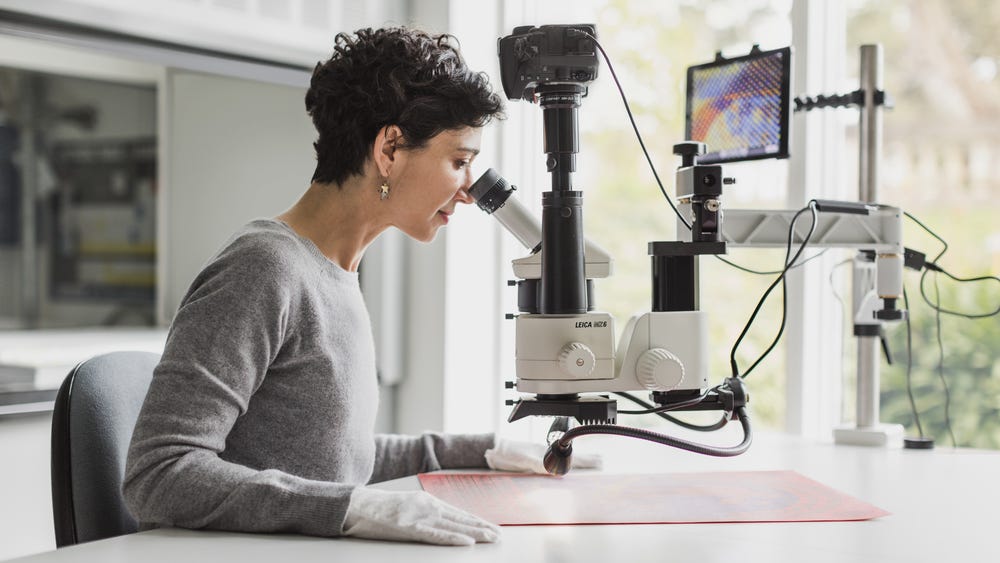Person looking through microscope at paper