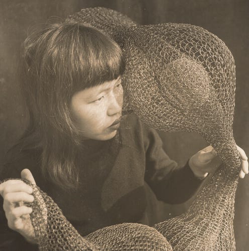 Photograph of Ruth Asawa holding a looped wire sculpture, taken by Imogen Cunningham