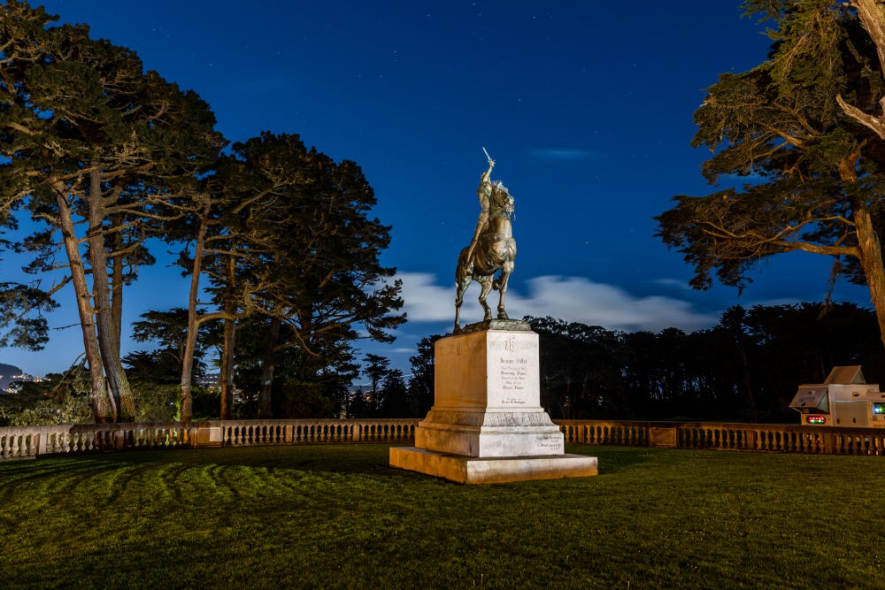 statue of a woman on a horse at night