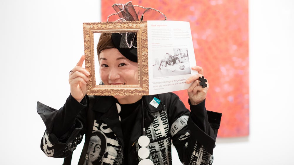 Asian woman looking through a frame in a brochure