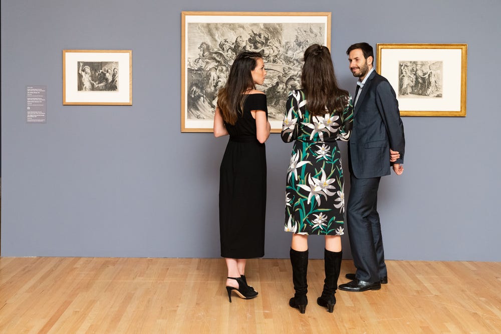 a group of three looking at an artwork in a gallery