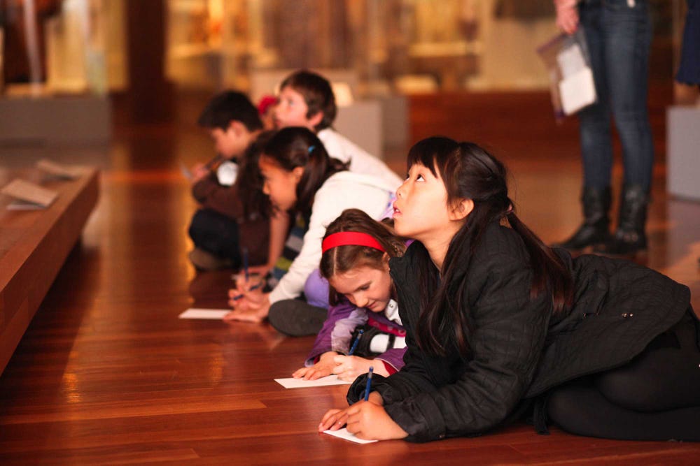Students working on activities while lying on the museum floor