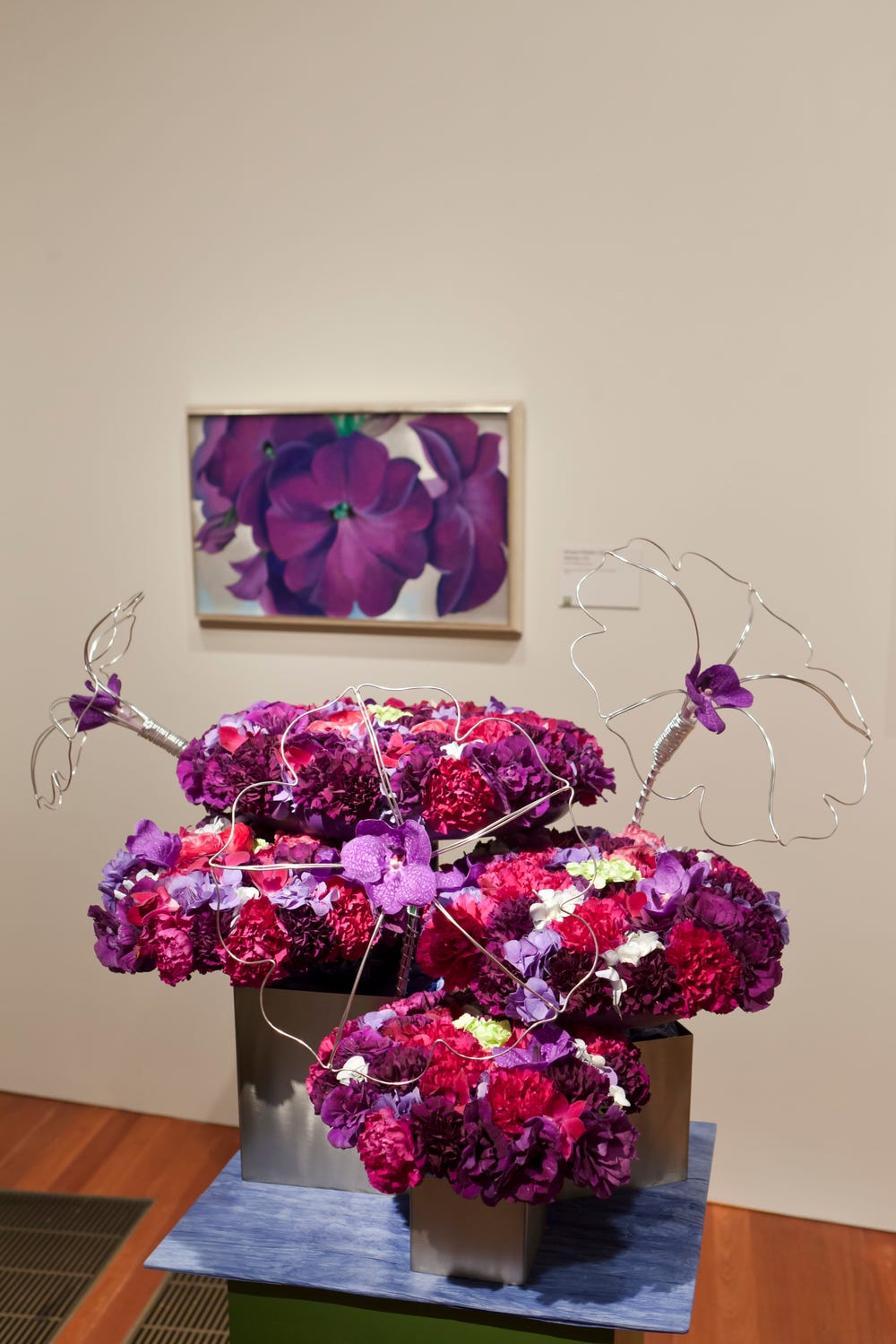 Photograph of purple, red, and pink flowers in style of painting of purple flowers in background.