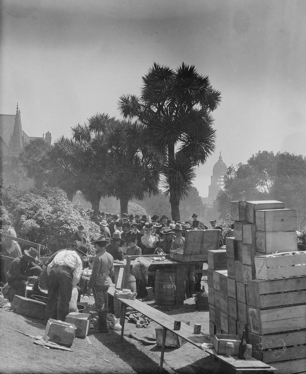 a long line of people awaits their rations in Jefferson Square with the ruins of the old City Hall looming in the background