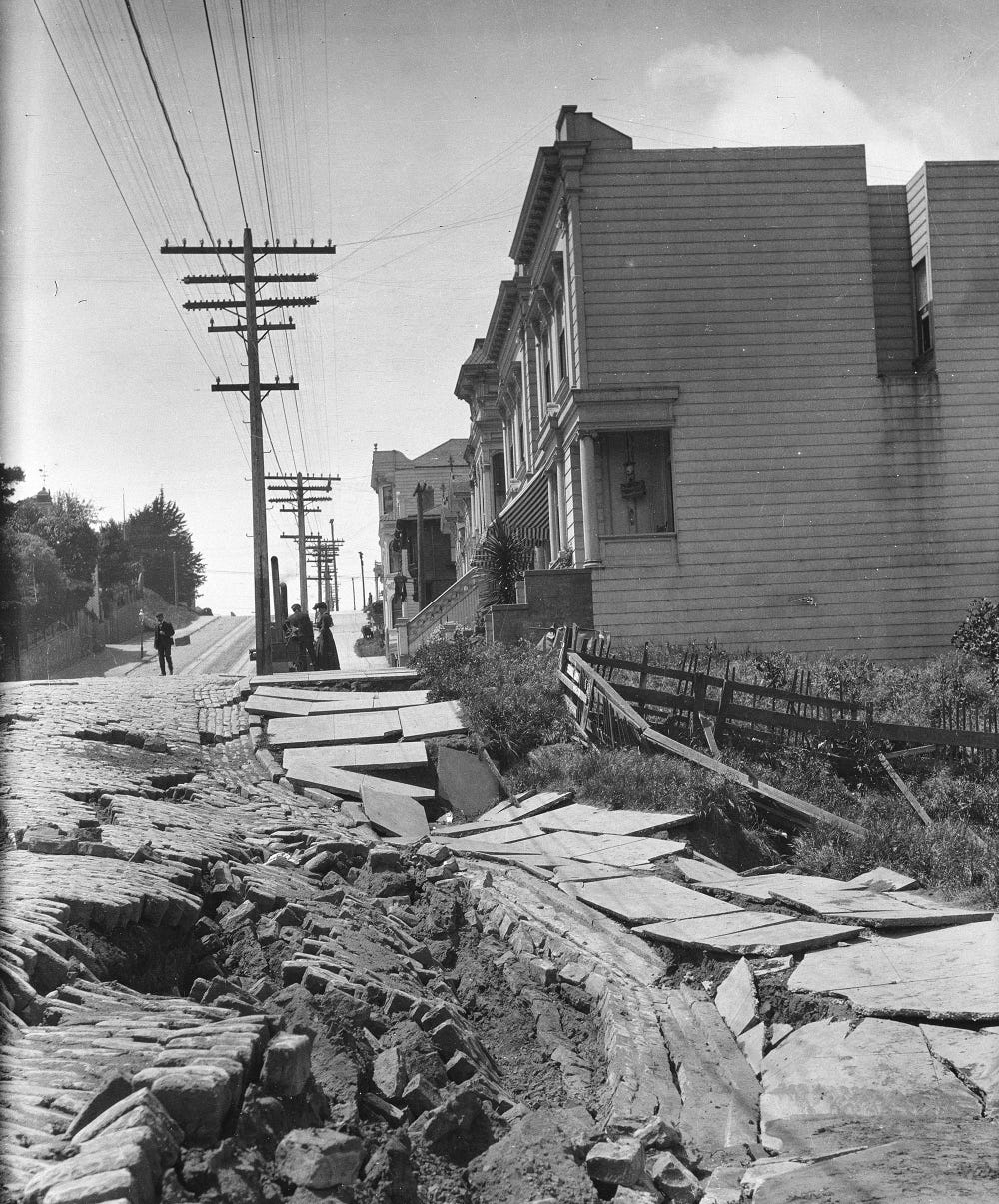 broken up street with houses and power lines in background