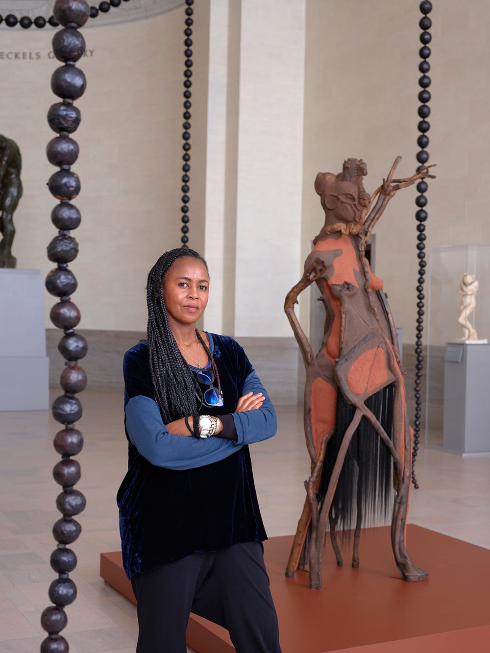 woman posing with her arms crossed in front of a sculpture