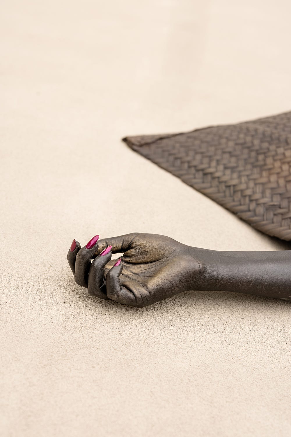 close up of a sculpture's hand with nail polish on the ground