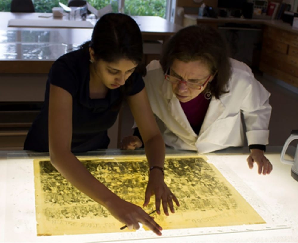 two women examine an artwork