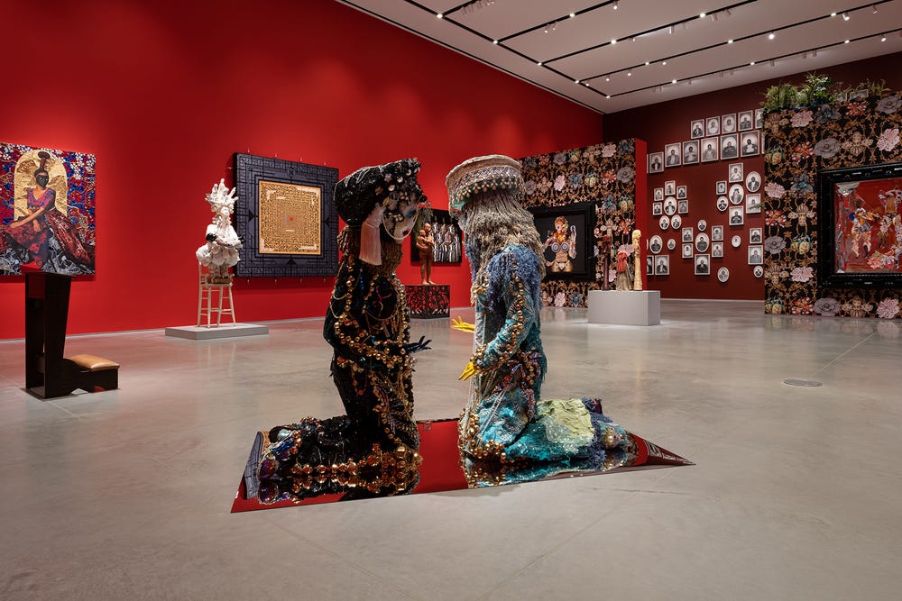 gallery with red walls and two sculptures in the foreground