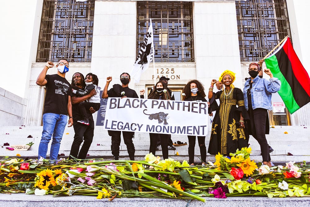 group holding a "Black Panther Legacy Monument" banner