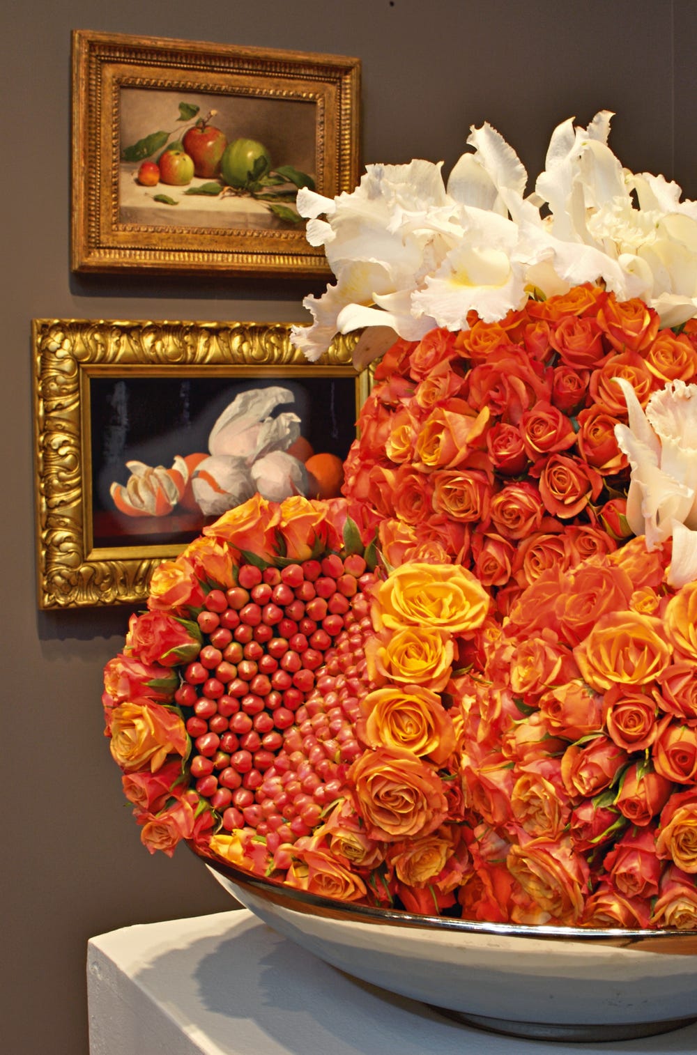 Photograph of red floral arrangement with corresponding painting in background.