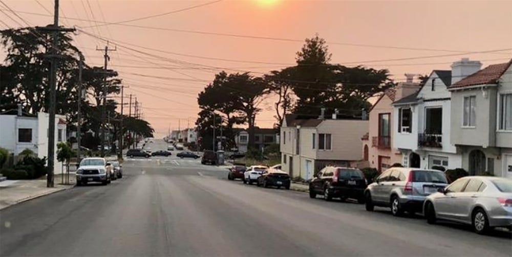 Photo of street lined with houses and cars at sundown