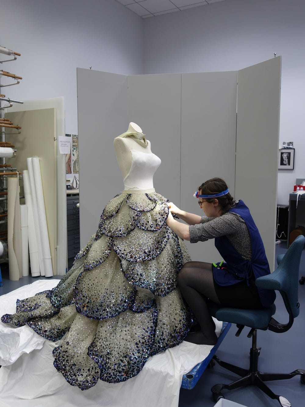 a woman works on the petals of a beaded skirt