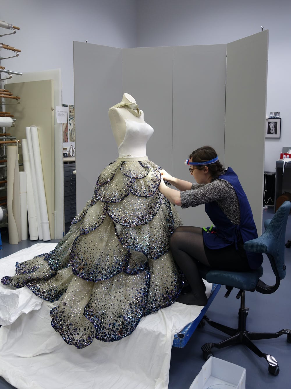 a woman works on the petals of a beaded skirt