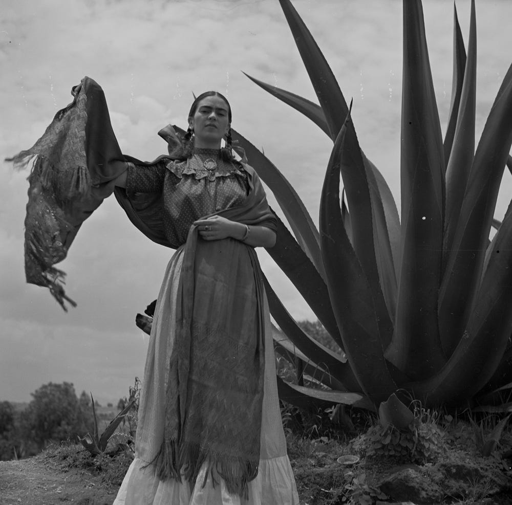 black and white photograph of Frida Kahlo standing next to an agave plant