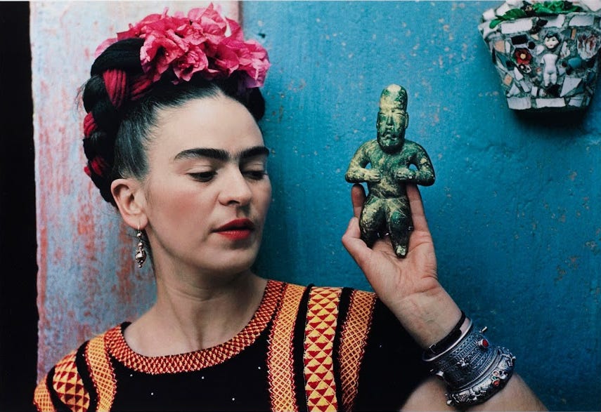 Woman with flowers in hair holding green figurine.