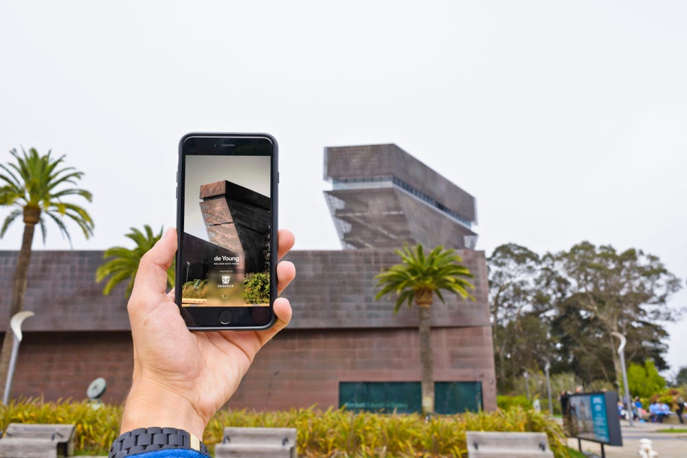Photograph of phone held up in front of de Young museum.