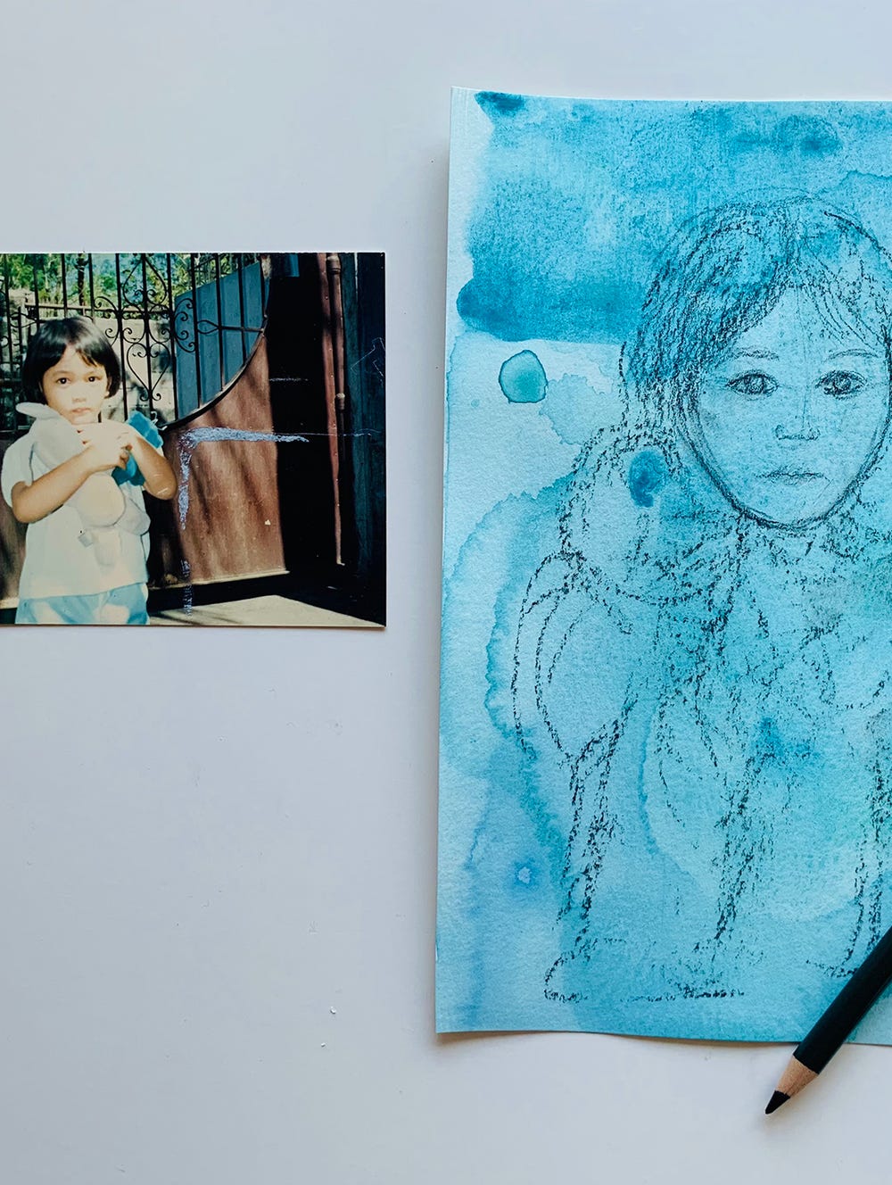 Photograph of young child next to blue painting of photograph
