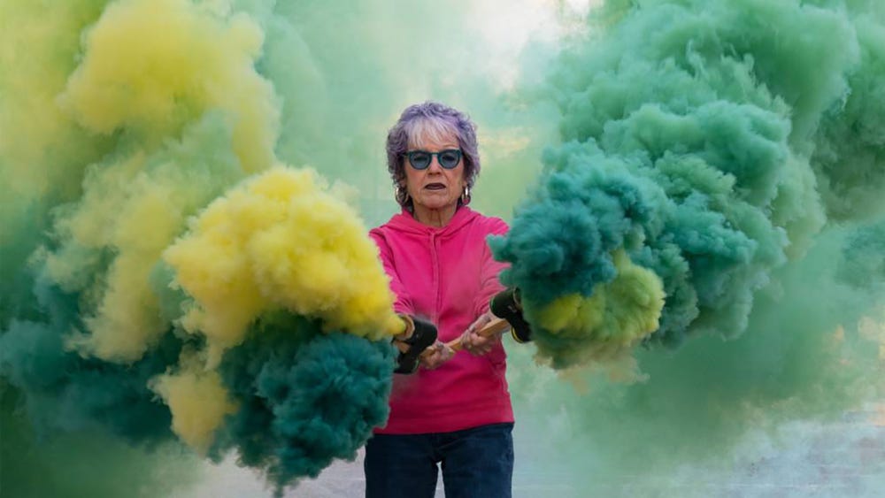 Judy Chicago surrounded by green and yellow smoke
