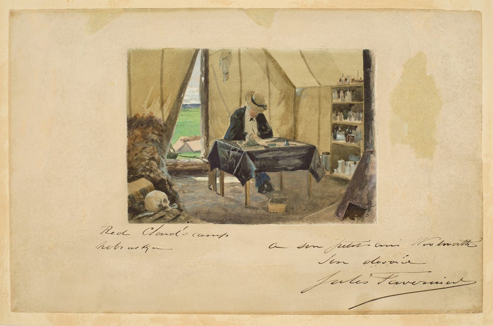 Man sitting at a table inside a tent writing on a piece of paper