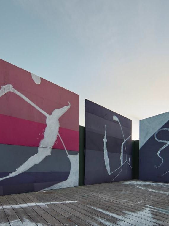 Photograph of large-scale colorful paintings displayed outdoors.
