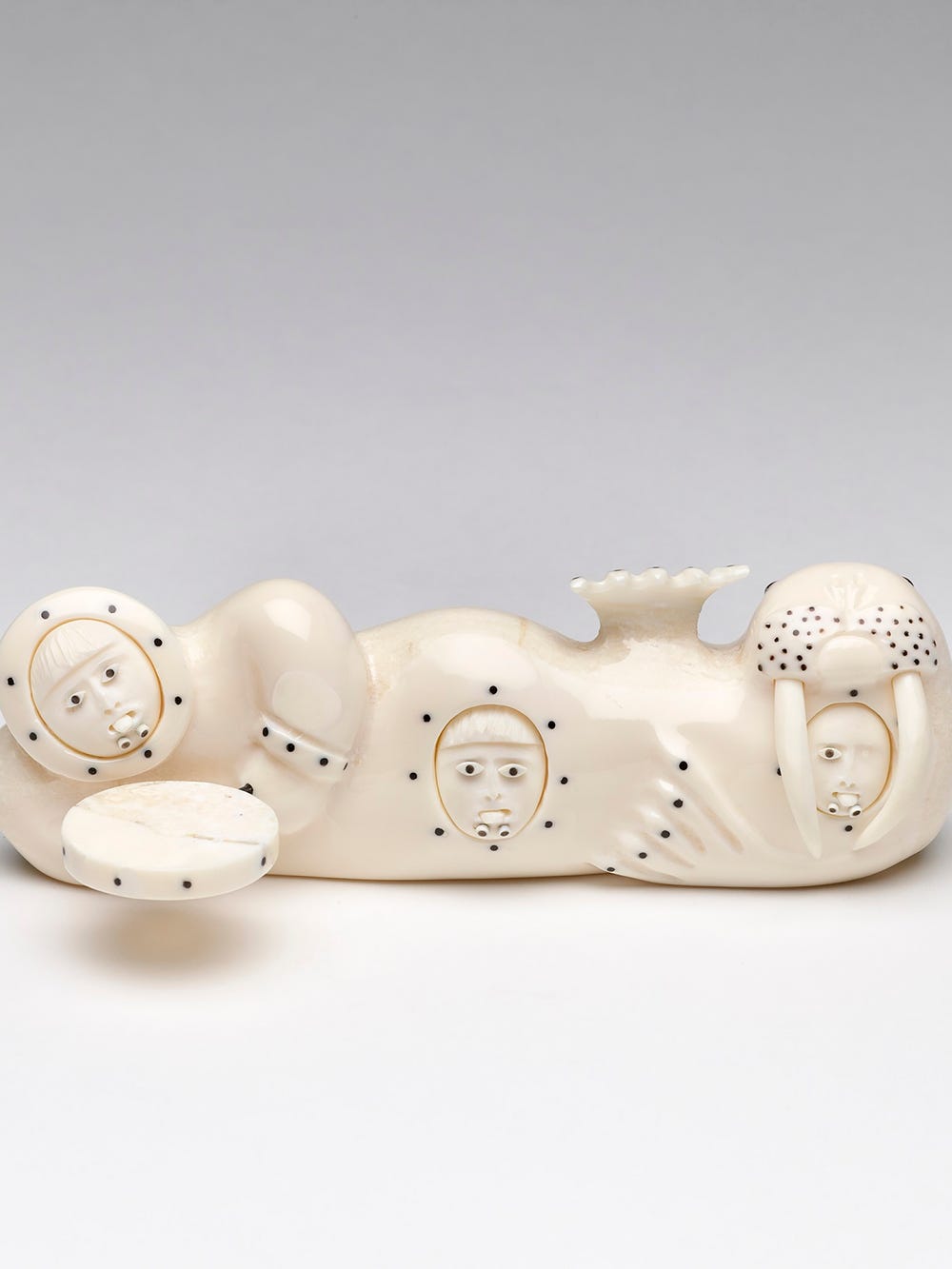 Figurine that is both a drummer and walrus with three faces looking out of their belly