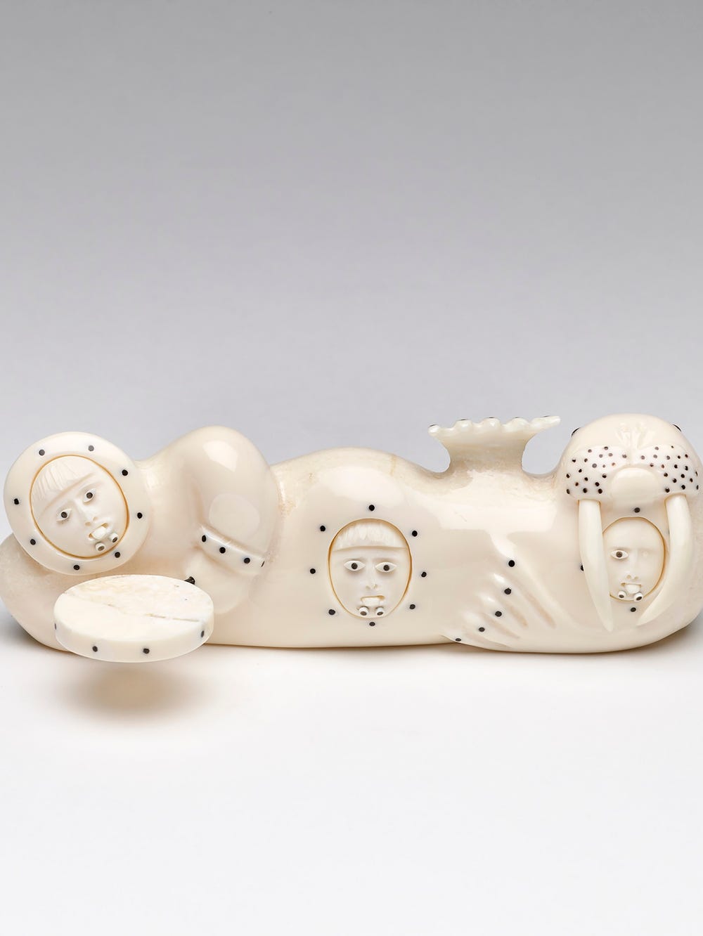 Figurine that is both a drummer and walrus with three faces looking out of their belly