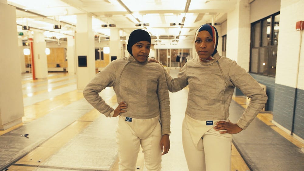 video still showing two women in fencing outfits in a subway