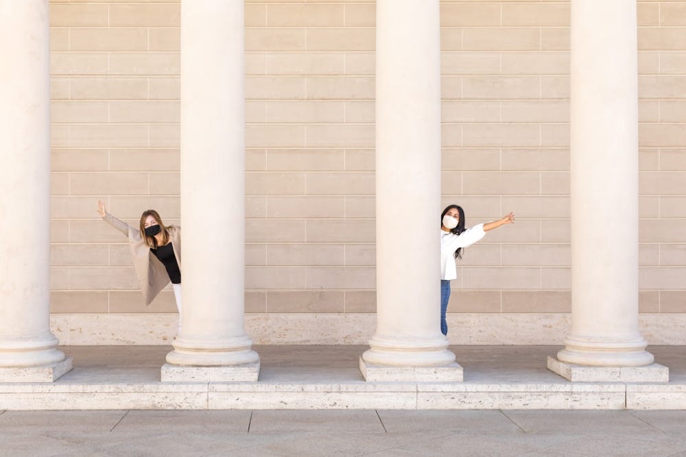 Two people posing outside in between large columns