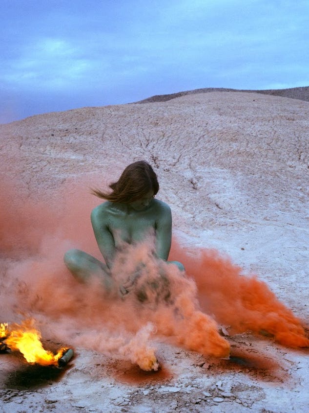 Photograph of woman sitting in orange smoke