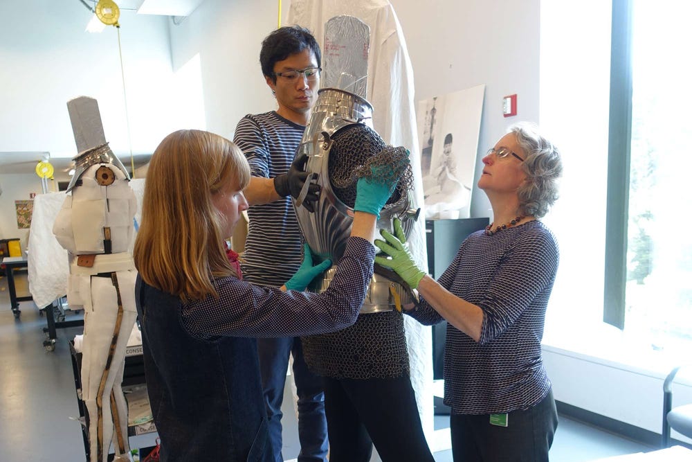 Objects conservators Colleen O’Shea and Jane Williams and mountmaker Mike Lai check the fit of the armor on its modified support and how well new mounts are supported.