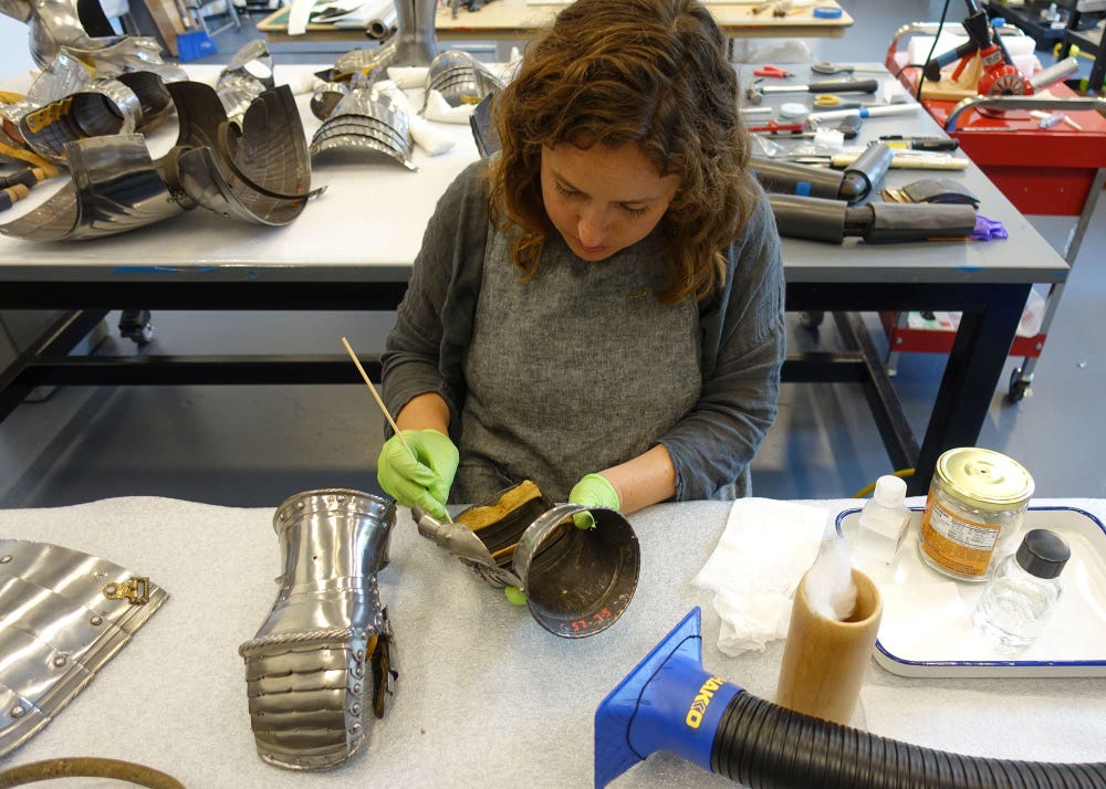Assistant conservator Jena Hirschbein uses solvents to reduce fingerprints and light corrosion on the surfaces of the disassembled armor.