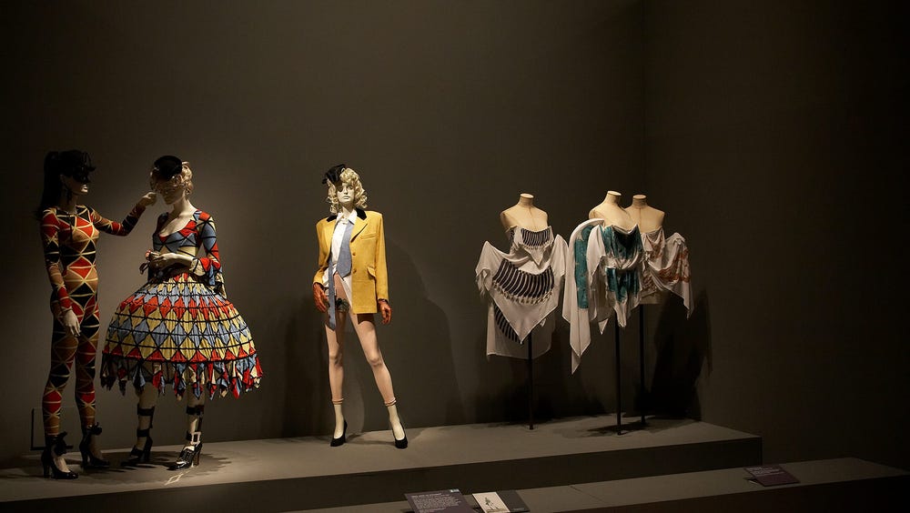 Photograph of colorful dresses and suits on display at museum.