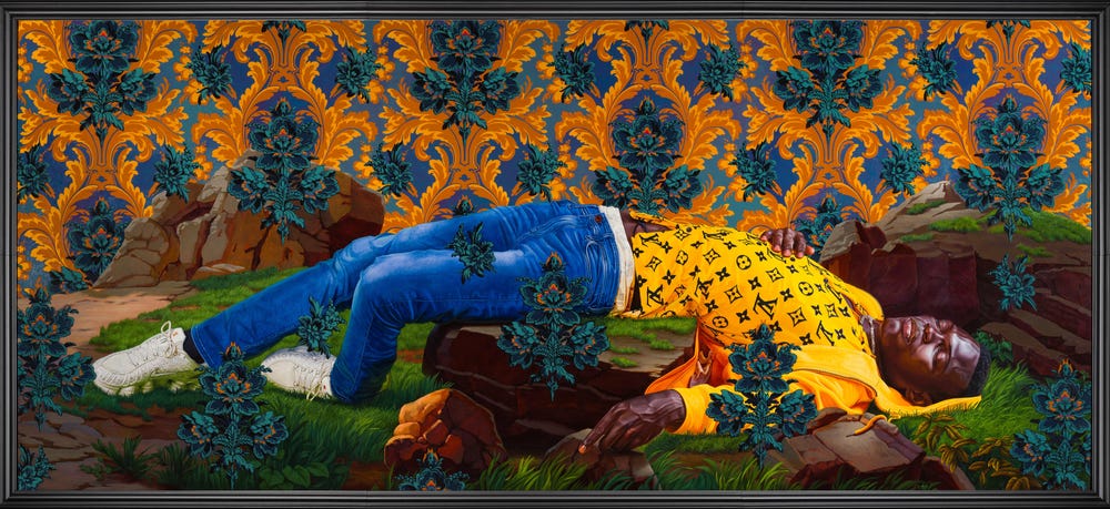 Man with his eyes closed laying on a grassy ground, in front of a colorful wallpaper backdrop
