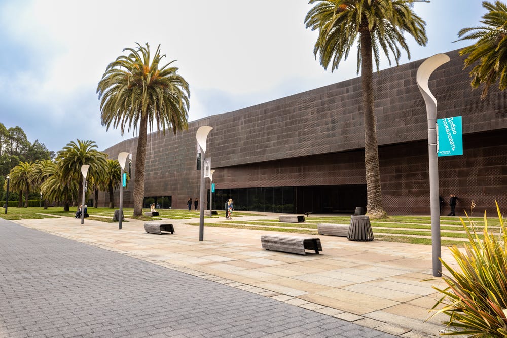 front of the de Young museum, with benches and palm trees