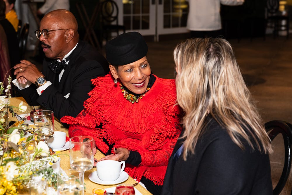 woman in red top talking at a table at a black tie dinner