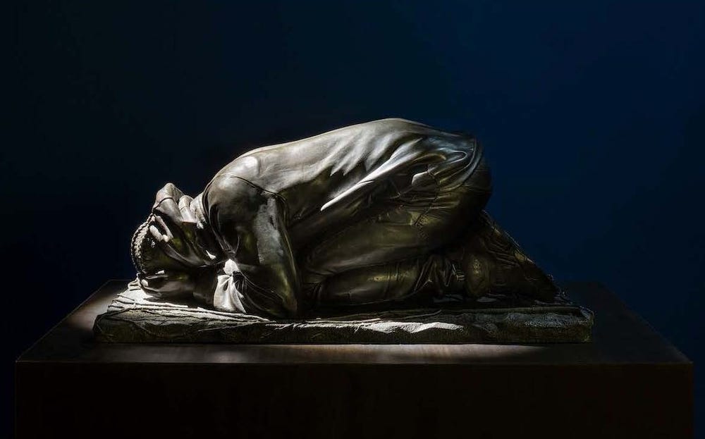 Bronze sculpture of a young person crouching with their face in their hands