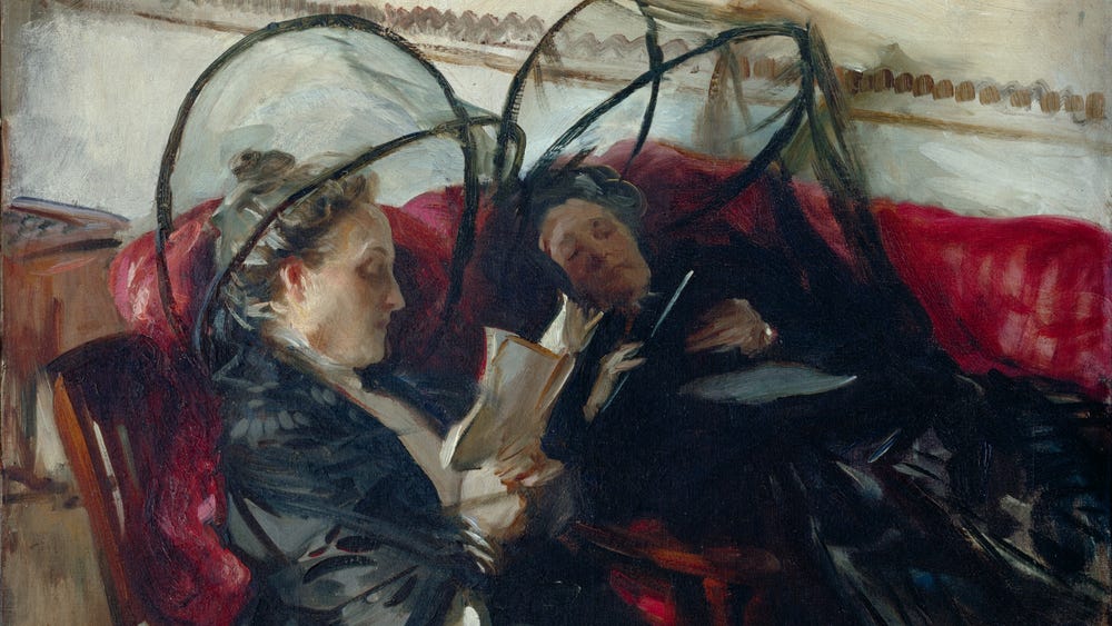 Two women seated in chairs underneath mosquito nets reading books