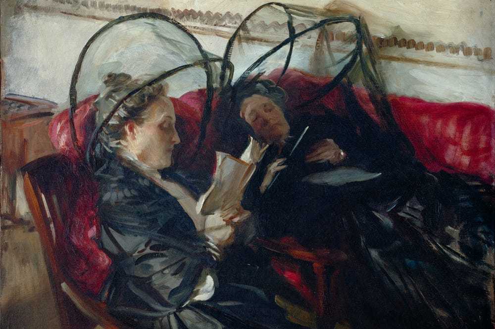 Two women seated in chairs underneath mosquito nets reading books