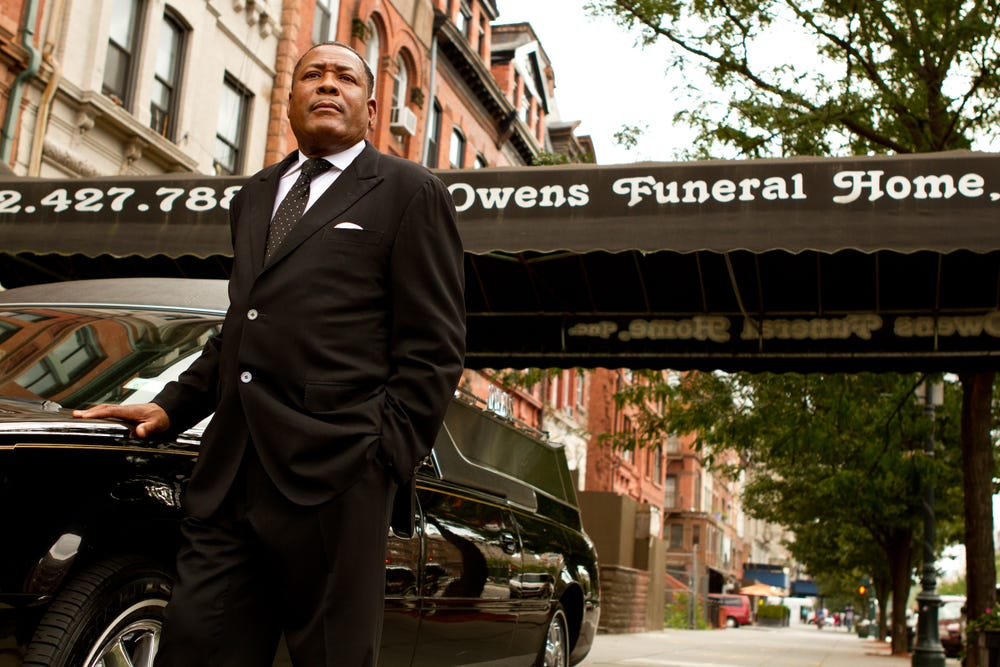 Man in a black suit outside of a funeral home in New York